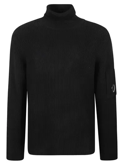 C.p. Company Ribbed Knit Roll Neck Sweater With Signature Lens Detail And Zip Pocket In Black