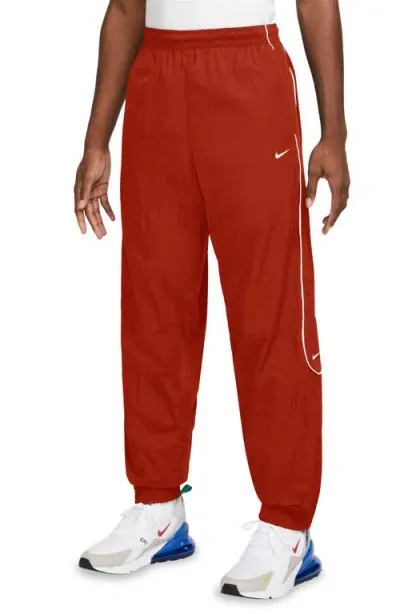 Nike Solo Swoosh Water Repellent Track Pants In Dragon Red/white